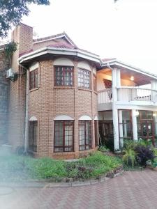 duży ceglany budynek z oknami wychodzącymi na ulicę w obiekcie Tjibelu's Nest Guest Home w mieście Lobatse