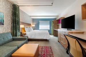 ein Hotelzimmer mit einem Bett und einem Flachbild-TV in der Unterkunft Home2 Suites by Hilton Bangor in Bangor