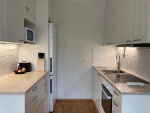 cocina blanca con fregadero y nevera en Tapiola Hill Apartment 2 bedroom and 1 living with private parking, en Espoo