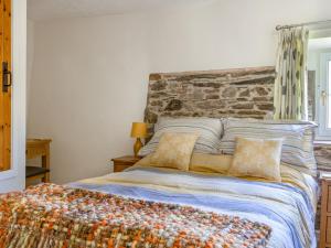 um quarto com uma cama com uma parede de pedra em Sandpiper Cottage em Salcombe