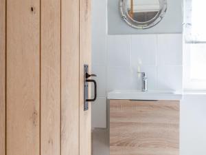 uma porta de casa de banho com um lavatório e um espelho em Sandpiper Cottage em Salcombe
