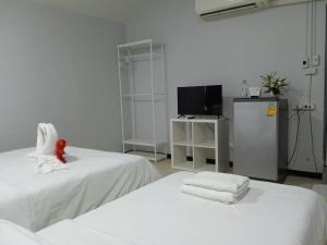 een witte kamer met 2 bedden en een televisie bij NK Guesthouse 1 in Klong Toi