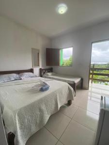 a bedroom with a bed and a large window at Pousada Toca da Coruja in Bonito