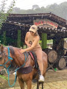 Eine Frau reitet ein Pferd im Regen in der Unterkunft Pousada Toca da Coruja in Bonito