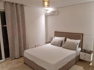 a bedroom with a large white bed and a window at Le 6éme in Sousse
