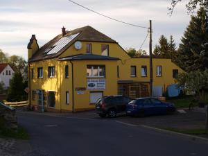 a yellow building with two cars parked in front of it at Pension Partzsch in Siebenlehn