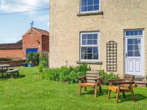 a yard with benches and tables in front of a building at Foston Grange Cottage in Bulmer