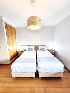 a bedroom with two beds and a chandelier at Casa Pedra da Nau- 2 bedroom APT @Figueira da Foz in Buarcos