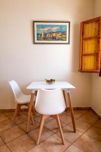 a white table and two white chairs in a room at Ostria Caldera Studios in Oia