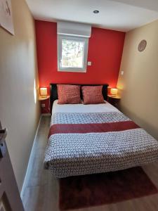 La chaumière في Longues-sur-Mer: غرفة نوم بسرير بجدار احمر