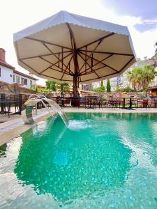 a pool with an umbrella and a fountain at Necip Bey Konağı in Antalya