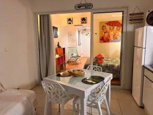 a kitchen with a table and chairs and a refrigerator at Studio Le Frangipanier in Saint-François