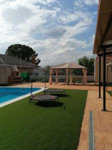a pool with two picnic tables and a gazebo at Hermosa Casa Vacacional La Promesa in Escalona