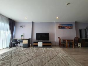 a living room with a television and a table and chairs at BEACH FRONT modern room + Free hi speed Wi-Fi in Ban Chak Phai