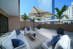 a rooftop patio with a couch and an umbrella at Cheval Maison - The Palm in Dubai