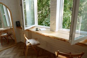 Pokój z 2 oknami i 2 drewnianymi krzesłami w obiekcie Passage Apartment w Iwano-Frankiwsku