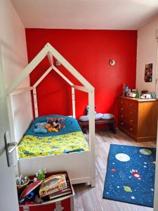 a bedroom with a bunk bed with a red wall at Maison piscine à 15m du Stadium in Toulouse