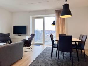 uma sala de estar com um sofá, uma mesa e cadeiras em Modern Spacious 3 Bedroom Apartment At Richard Mortensens Vej With Balcony Close To The Royal Arena And Fields em Copenhaga