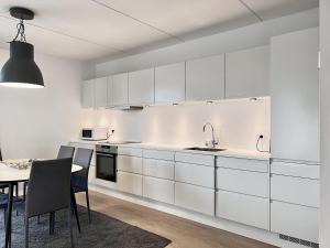 uma cozinha com armários brancos e uma mesa com cadeiras em Modern Spacious 3 Bedroom Apartment At Richard Mortensens Vej With Balcony Close To The Royal Arena And Fields em Copenhaga