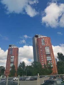 two tall buildings with cars parked in a parking lot at SolarisStudioApartments near the Airport in Riga