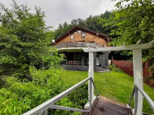 une maison en bois avec une terrasse couverte et une clôture dans l'établissement Casa River, à Băişoara