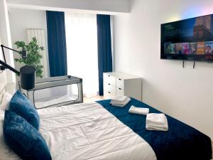 a bedroom with a bed with blue pillows and a tv at Veli Apartments 348 Infinity in Mamaia Sat/Năvodari +19 photos