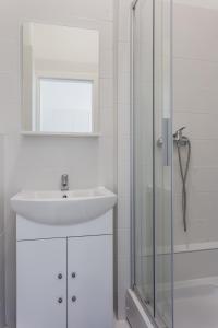 a white bathroom with a sink and a shower at Mika Apartment and Studios in Zagreb