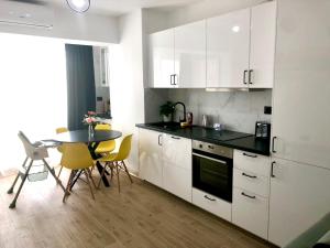 a kitchen with white cabinets and a table with chairs at Veli Apartments 348 Infinity in Mamaia Sat/Năvodari