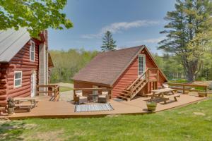 Cabaña de madera con terraza y mesas de picnic en Unique Maine Log Cabin with Trout Ponds and Sauna! 