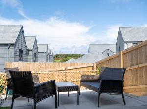 três cadeiras e uma mesa num pátio com uma cerca em The Waves em Newquay