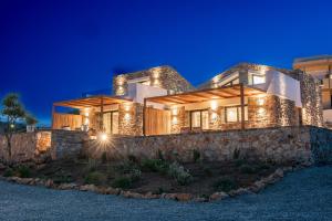 una casa iluminada por la noche con una pared de piedra en Agro Nostro-Agave with superb view en Ágios Nikólaos