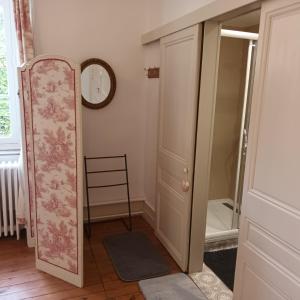 a bathroom with a mirror and a clock on the wall at Petit manoir de la berthenlaire in Baincthun