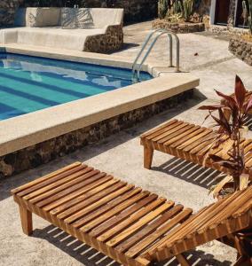 two wooden benches sitting next to a swimming pool at Hotel Pimampiro in Puerto Baquerizo Moreno