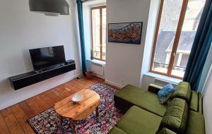 a living room with a green couch and a table at Au Fil de soi in Morlaix