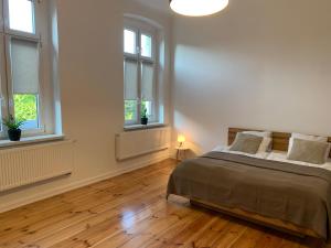 a white bedroom with a bed and two windows at Na skraju Rynku 110 m2 in Tarnowskie Góry