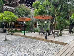 a patio with tables and chairs and umbrellas at EcoHostal Rio Piedra in El Zaino
