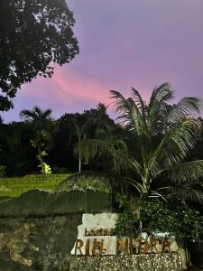 a sign with a palm tree in front of a fence at EcoHostal Rio Piedra in El Zaino