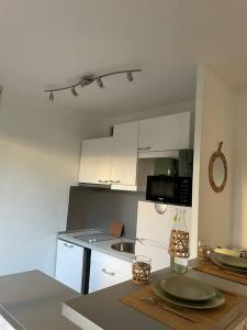 una pequeña cocina con armarios blancos y encimera en Studio 28 m2 & jardin privatif 20 m2, en Montigny-le-Bretonneux