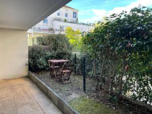 - une table de pique-nique et des chaises à côté d'une clôture dans l'établissement Studio 28 m2 & jardin privatif 20 m2, à Montigny-le-Bretonneux