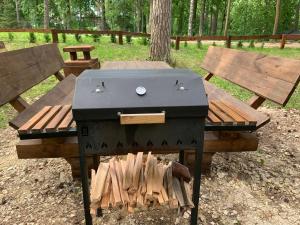 a barbecue grill sitting next to a wooden picnic table at Saules Krasti in Saulkrasti