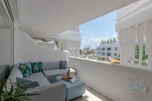 a white balcony with a couch and a view of a city at Puerto Marina Luxury 2BDR Apartment with Sea View in Benalmádena