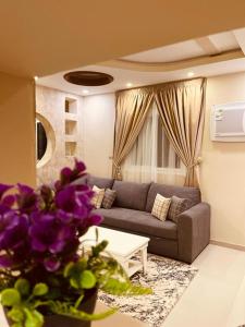 شقق الأجواء الفاخرة في المدينة المنورة: غرفة معيشة مع أريكة وطاولة مع زهور أرجوانية