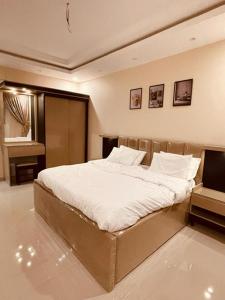 شقق الأجواء الفاخرة في المدينة المنورة: غرفة نوم بسرير كبير مع شراشف بيضاء
