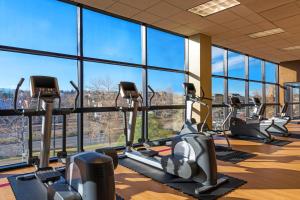 un gimnasio con filas de máquinas cardiovasculares y grandes ventanas en Sheraton Denver West Hotel, en Lakewood