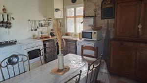 una cocina con una mesa con un jarrón. en Gîtes du Rouyre La Grange, en Réalmont