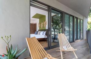 a room with two chairs and a bed on a balcony at Casa Taman by Kukun in Mexico City