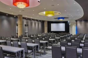 a conference room with tables and chairs and a screen at Aloft Richardson in Richardson