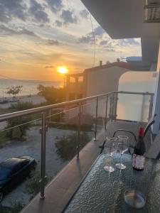 dos copas de vino en una mesa en un balcón con la puesta de sol en Villa Loukas en Loutsa