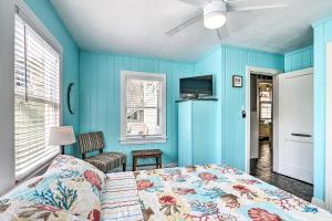 a bedroom with blue walls and a bed and a tv at Historic Galveston Hideaway, Walk to the Beach! in Galveston
