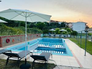 a swimming pool with a table and an umbrella at Apartments Spartacus in Polychrono +46 photos
